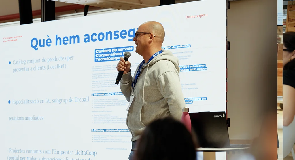 Un ponente presenta los resultados del sector de las cooperativas tecnológicas frente a la pantalla «Lo que hemos conseguido».
